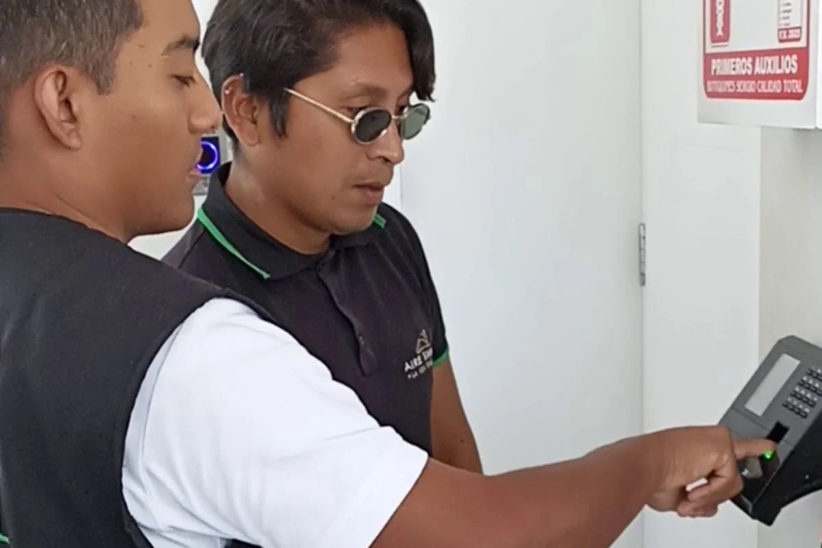 Empleado marcando asistencia con huella digital en terminal biométrico de empresa peruana
